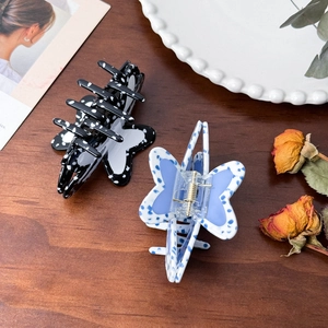 Elegant acetate butterfly hair claw clips with polka dot patterns on a vintage wooden desk
