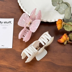 Elegant large acetate claw clips in pink marble and cream white on a rustic wood background