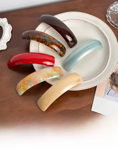 Set of six colorful geometric hair clips in a chic ceramic tray on a vintage wooden desk