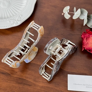 Set of two marbled acetate hair claws with premium metal mechanism on wooden surface