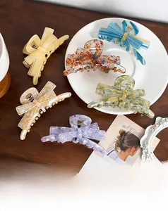 Detailed view of large acetate bow hair claws in six assorted marble colors on a table
