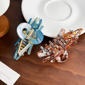 Elegant large acetate butterfly hair claws with tortoiseshell and marble patterns on wooden table