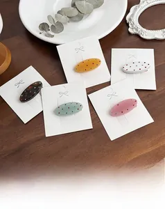 Mini pinces à cheveux ovales en acétate avec strass sur fond en bois rustique