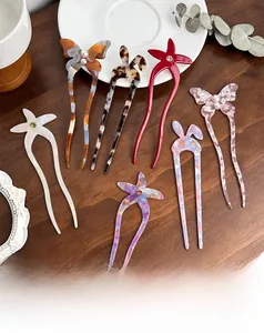 Detailed macro view of U-shaped hairpins with acetate butterfly and pearl embellishments