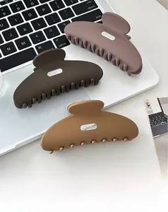 Three matte resin hair claws in earth tones shown on a silver laptop and white desk
