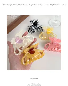 Detail view of acetate butterfly hair claw clips with heart patterns in four colors