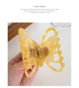 Detailed shot of an amber acetate butterfly hair claw clip with golden spring mechanism