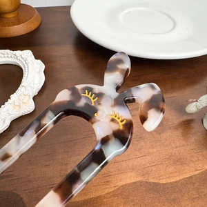 U-shaped acetate hair pin with marble texture and rabbit ear design on wooden table