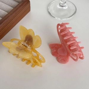 Acetate butterfly hair claws in amber and pink marble texture on a white surface