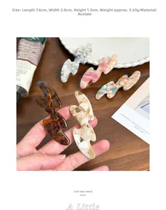 Detailed view of wavy acetate hair clips in five colors on a wooden surface