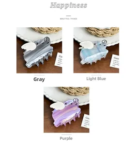 Trois pinces à cheveux cochons ailés en gris, bleu clair et violet sur fond chaleureux