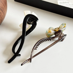 Elegant bow hair clips and acetate claw set for versatile women's hairstyles in soft lighting