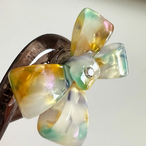 Elegant tortoiseshell acetate hair claw clip with colorful translucent resin bow and crystal