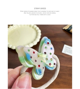 Close-up of a gradient butterfly hair tie with colorful rhinestones on a wooden desk