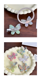 Detailed view of rhinestone butterfly hair clip and elastic band on a ceramic tray