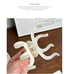 Close-up of cream white acetate octopus hair claw with grey polka dots and metal spring