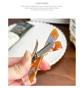 Close-up of vintage acetate hair clip with amber texture and silver metal duckbill base