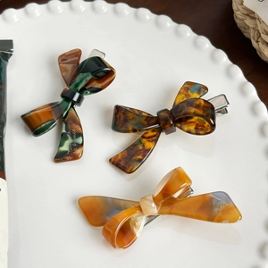 Vintage acetate bow hair clips in tortoiseshell and marble patterns on a white plate
