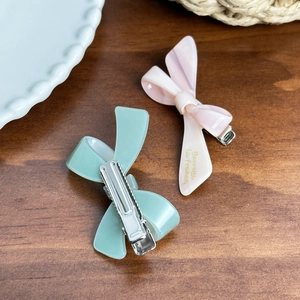 French vintage acetate bow hair clips in mint green and marble pink on a wooden surface