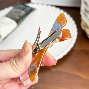 Acetate tortoise shell hair clip with blue highlights shown in a lifestyle hand-held view