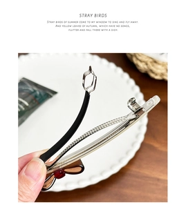 Detail view of the metal spring clip mechanism with elegant bow and bead accents
