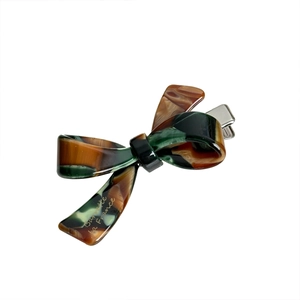 Retro acetate bow hair clip with tortoiseshell pattern and polished finish on white backdrop