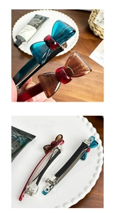 Macro detail of French handmade acetate bow hair clips in amber and dark cyan