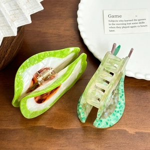 Green and white fruit acetate hair claw clips with metal spring on wooden desk