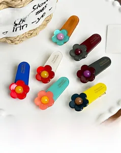 Detailed macro view of acetate flower hair clips in seven colors on a white ceramic plate