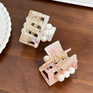 Pinces à cheveux carrées en acétate avec perles en crème et rose sur bureau en bois