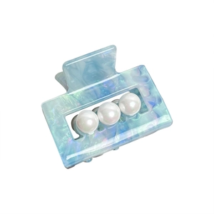Pince à cheveux carrée en acétate bleu clair nacré avec perles sur fond blanc minimaliste