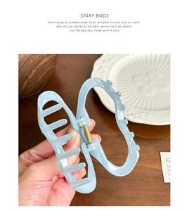 Gros plan d'une pince à cheveux bleue givrée au design papillon sur une table
