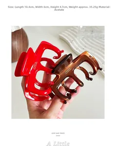 Vue détaillée de grandes pinces à cheveux en acétate rouge et ambre mesurant 10,4 cm