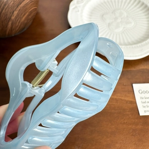 Pince à cheveux évidée bleu clair mat avec un design ondulé élégant sur un bureau
