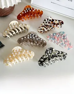Flat lay of seven assorted acetate claw clips with elegant faux pearl embellishments