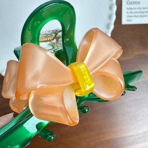 Large green acetate hair claw clip with contrast pink bow and yellow center accent