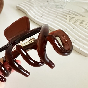 Pince à cheveux spirale marron translucide avec ressort doré sur plateau décoratif