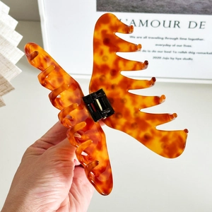 Large amber tortoiseshell acetate hair claw clip for thick hair styling held in hand