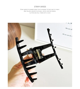 Close-up of black geometric hair claw clip with golden metal spring for elegant updo styles