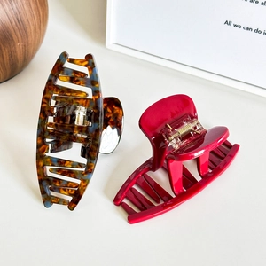 French style tortoise shell and deep red acetate hair claws set on a white surface