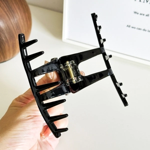 Classic glossy black acetate hair claw clip with sturdy gold metal spring for women