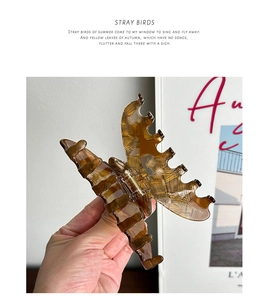 Detail view of a large amber acetate hair claw clip with vintage resin texture and teeth