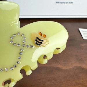 Elegant pale yellow hair claw clip with crystal rhinestones and a gold bee accent