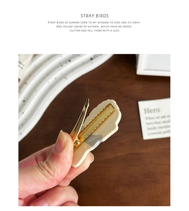 Close-up of cream-colored acetic acid hair clip with golden metal duckbill structure