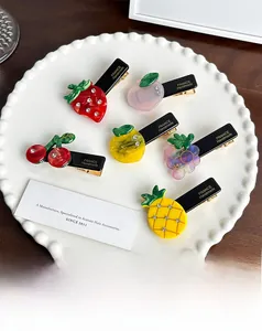 Close-up of handmade acetate fruit hair clips with sparkling rhinestones and gold engraving