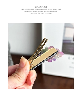 Detail of purple acetate flower hair clip with gold metal duckbill base held in hand