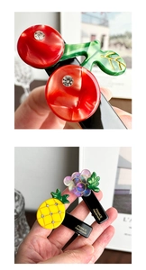 Detailed macro view of handmade fruit hair clips with rhinestones and gold lettering