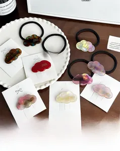 Dettaglio del fermaglio e dell'elastico in acetato a forma di nuvola con trama marmorizzata e logo