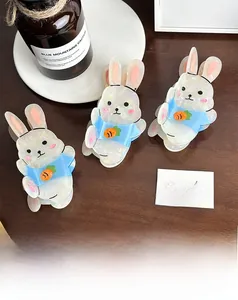 Détail de trois pinces à cheveux en acétate en forme de lapin sur un support en bois