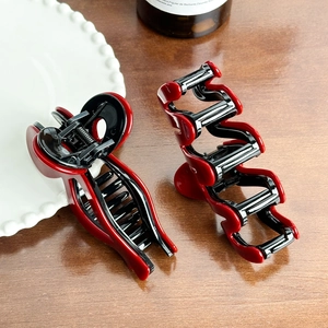 Elegant red and black resin hair claw clips set on a rustic wooden table background